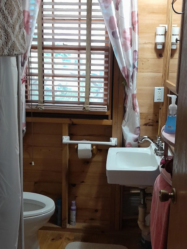 bathroom with sink, wood walls, and toilet