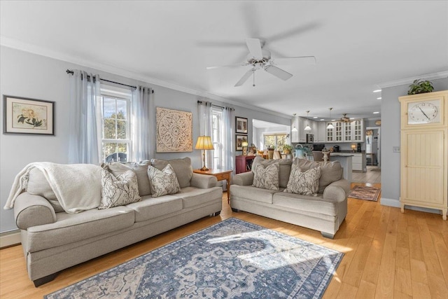 living room with ornamental molding, ceiling fan, and light hardwood / wood-style floors