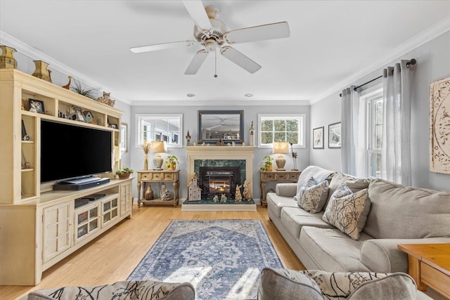 living room featuring ceiling fan, ornamental molding, a high end fireplace, and light hardwood / wood-style flooring