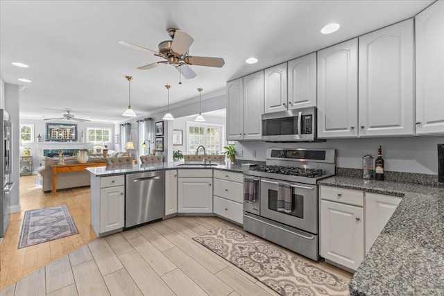 kitchen featuring white cabinetry, appliances with stainless steel finishes, kitchen peninsula, and decorative light fixtures