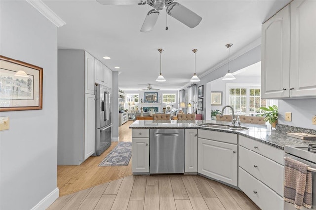 kitchen with stainless steel appliances, white cabinetry, sink, and decorative light fixtures