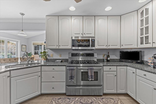 kitchen with sink, stainless steel appliances, dark stone counters, and white cabinets