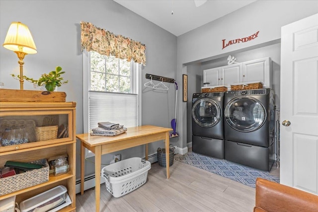 laundry area featuring baseboard heating, cabinets, light hardwood / wood-style flooring, and washing machine and clothes dryer