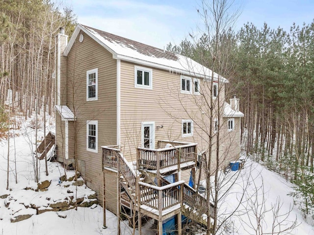 snow covered back of property featuring a wooden deck