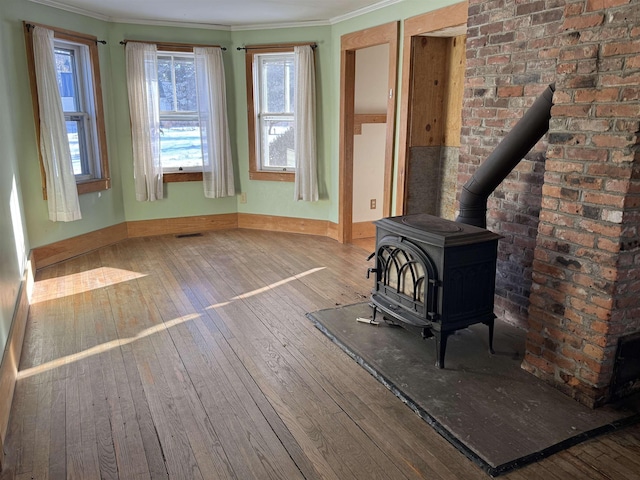 unfurnished living room featuring crown molding, hardwood / wood-style flooring, and a wood stove