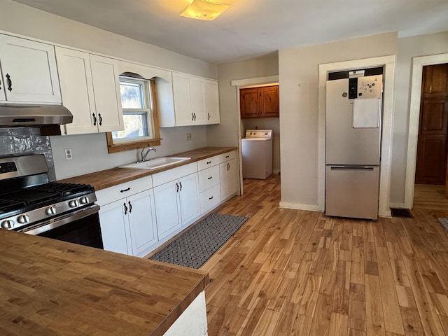 kitchen with refrigerator, washer / clothes dryer, sink, wooden counters, and stainless steel range with gas stovetop