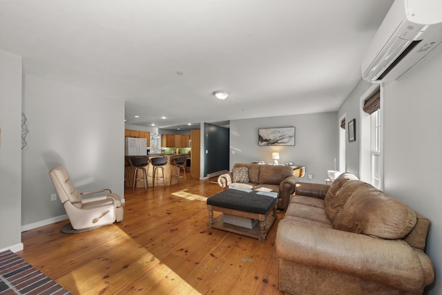 living room with a wall mounted air conditioner and light hardwood / wood-style flooring