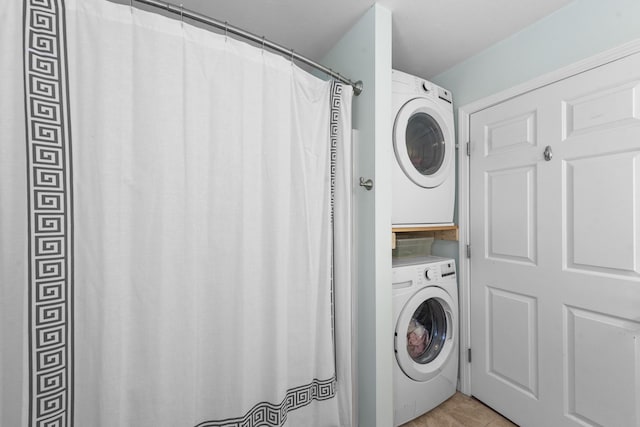 laundry area featuring stacked washer and dryer and light tile patterned floors