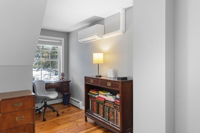 office space featuring light hardwood / wood-style flooring, a wall unit AC, and baseboard heating