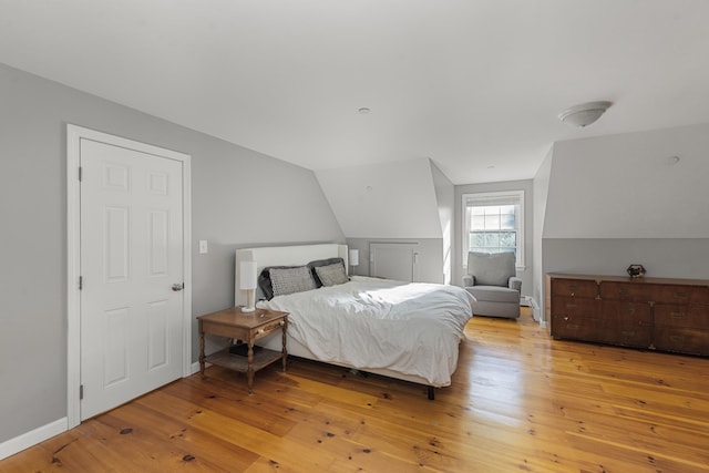 bedroom with vaulted ceiling and light wood-type flooring