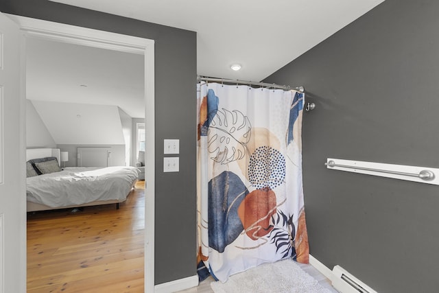 bathroom with lofted ceiling, a baseboard heating unit, and hardwood / wood-style floors