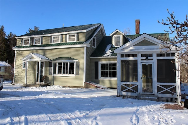 snow covered house with a sunroom