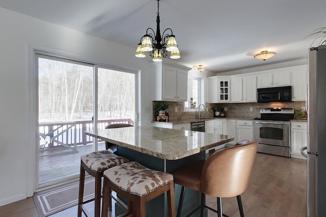 kitchen featuring pendant lighting, sink, a breakfast bar area, white cabinets, and stainless steel appliances