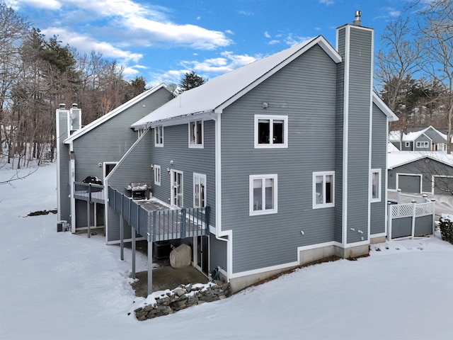 snow covered back of property with a deck