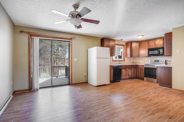 kitchen featuring sink, light hardwood / wood-style flooring, a baseboard heating unit, tasteful backsplash, and black appliances