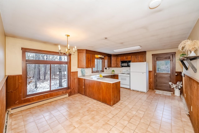 kitchen featuring hanging light fixtures, a baseboard radiator, wooden walls, kitchen peninsula, and white appliances