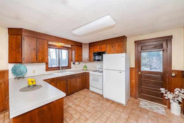 kitchen with sink, white appliances, and wood walls