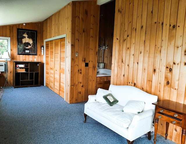 sitting room featuring carpet floors, vaulted ceiling, and wooden walls