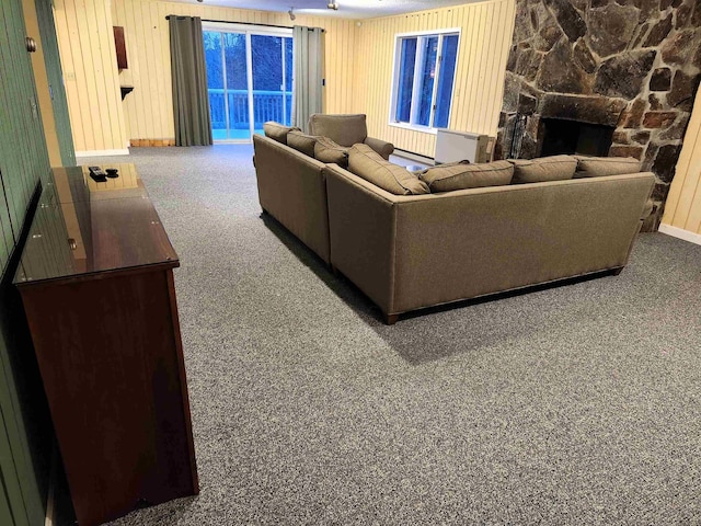 carpeted living room featuring a fireplace and wood walls