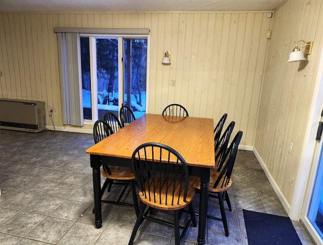 tiled dining area with a textured ceiling and wooden walls