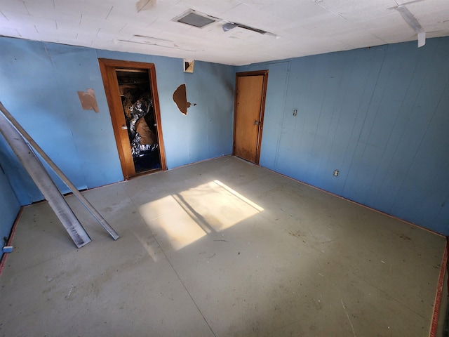 unfurnished room with concrete floors and wood walls