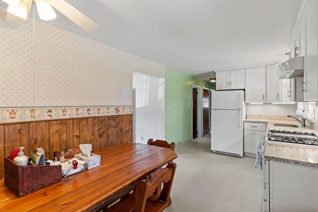 kitchen featuring white cabinetry, gas range, exhaust hood, and white fridge