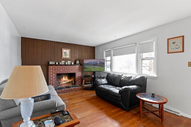 living room featuring a fireplace, light hardwood / wood-style flooring, and wooden walls