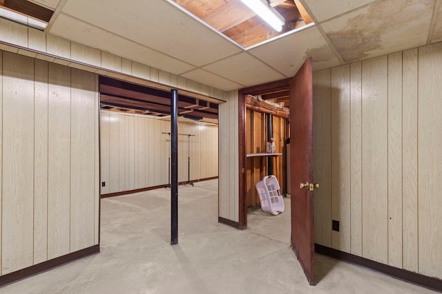 basement with wooden walls and a drop ceiling