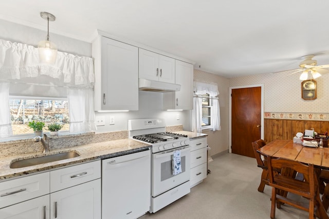 kitchen featuring sink, white appliances, white cabinetry, hanging light fixtures, and light stone countertops