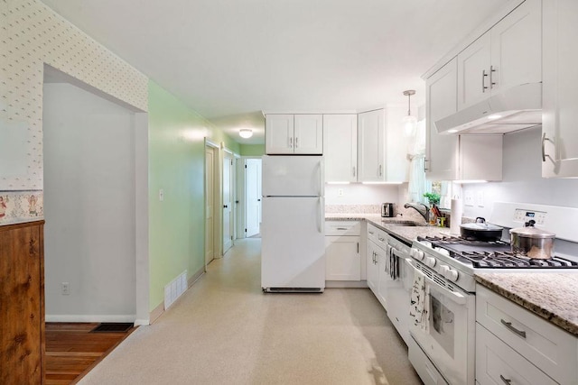 50 Suzanne Dr, Portsmouth, NH 03801 - kitchen with white appliances, under cabinet range hood, white cabinets, light stone countertops, and wallpapered walls