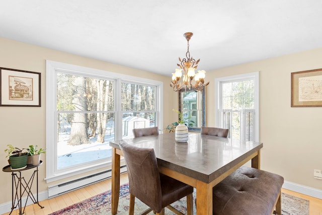 dining area with a healthy amount of sunlight, a baseboard heating unit, a chandelier, and light wood-type flooring