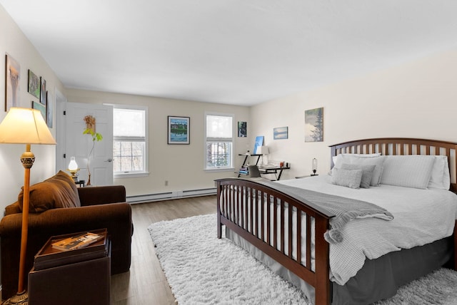 bedroom with a baseboard heating unit and light hardwood / wood-style floors