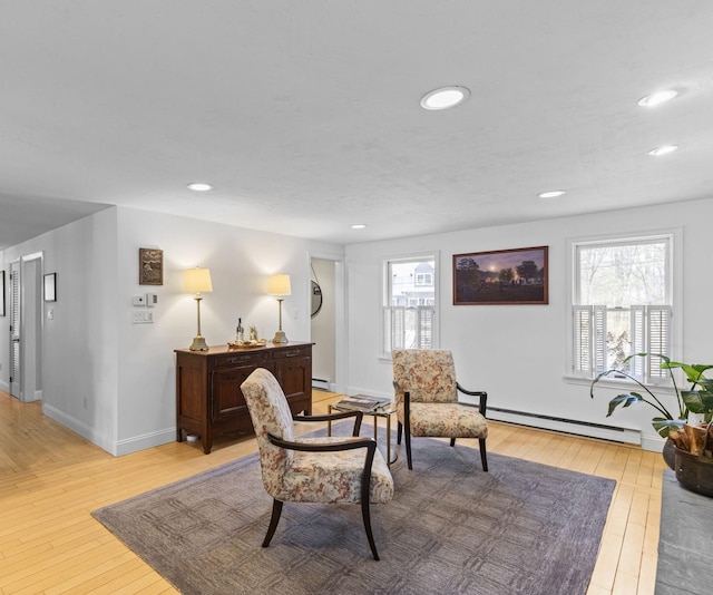 living area featuring a baseboard heating unit and light wood-type flooring