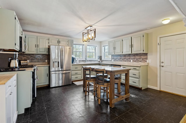 kitchen with hanging light fixtures, backsplash, sink, and appliances with stainless steel finishes