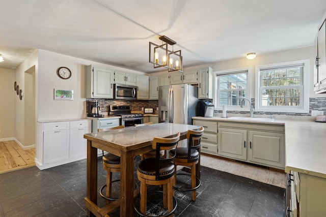 kitchen featuring decorative light fixtures, white cabinetry, sink, decorative backsplash, and stainless steel appliances