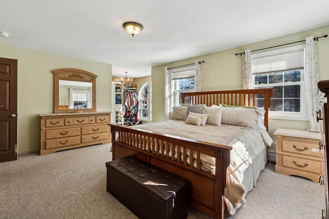 carpeted bedroom featuring a closet, a chandelier, and baseboard heating