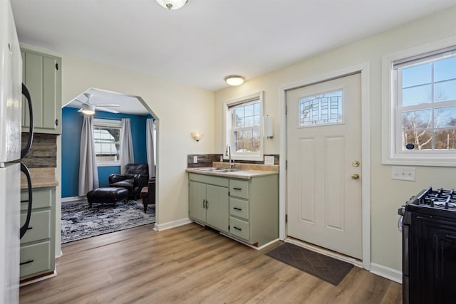 kitchen featuring sink, green cabinets, range with gas cooktop, and light hardwood / wood-style flooring