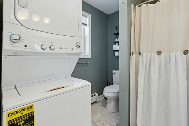 washroom featuring baseboard heating and stacked washer / drying machine