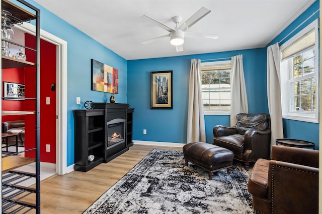 sitting room featuring a fireplace, wood-type flooring, and ceiling fan