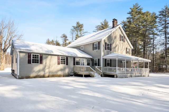 snow covered rear of property with a porch