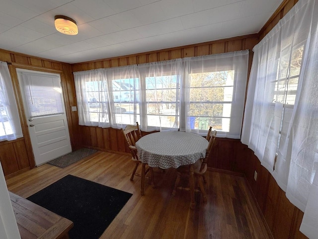 dining room featuring wood-type flooring, wooden walls, and a wealth of natural light