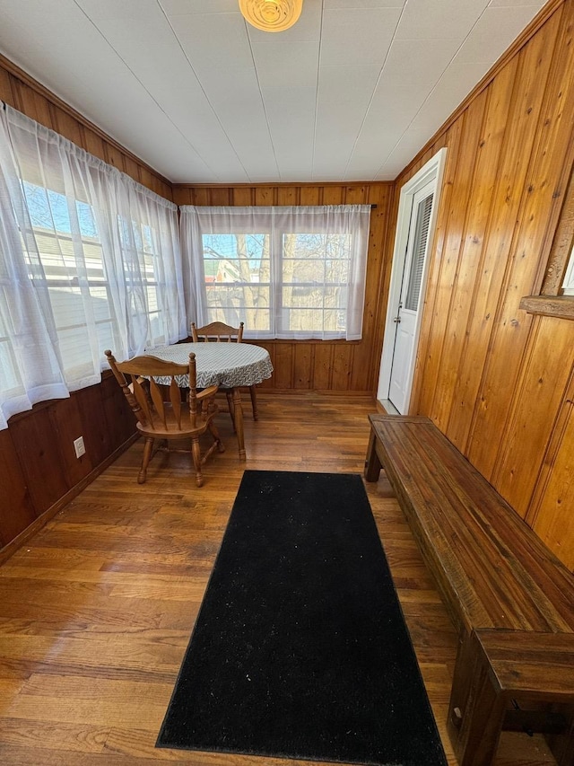 dining space with hardwood / wood-style flooring and wood walls