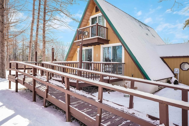 snow covered back of property with a balcony