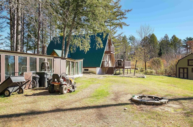 view of yard with a storage shed, a wooden deck, a sunroom, and a fire pit