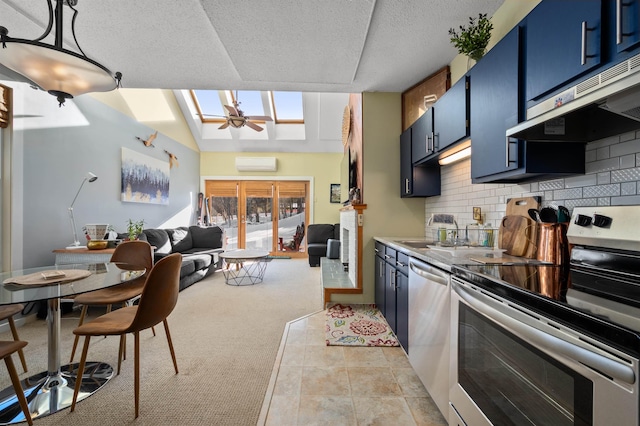 kitchen with appliances with stainless steel finishes, an AC wall unit, blue cabinets, backsplash, and hanging light fixtures