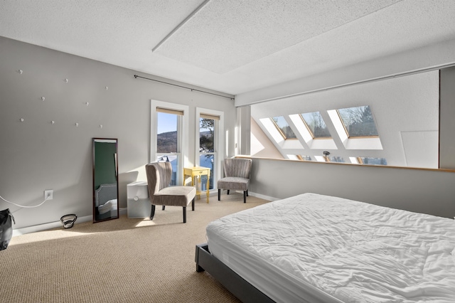 bedroom with a skylight, carpet floors, and a textured ceiling