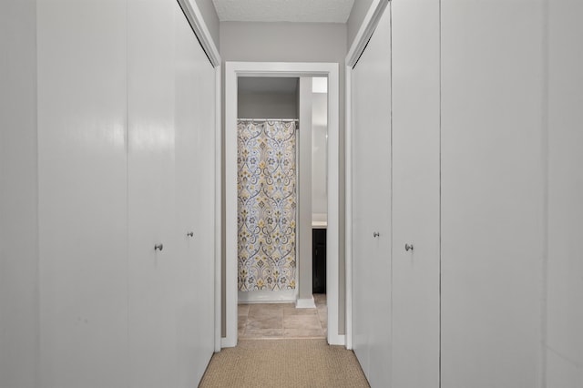 hall with light carpet and a textured ceiling