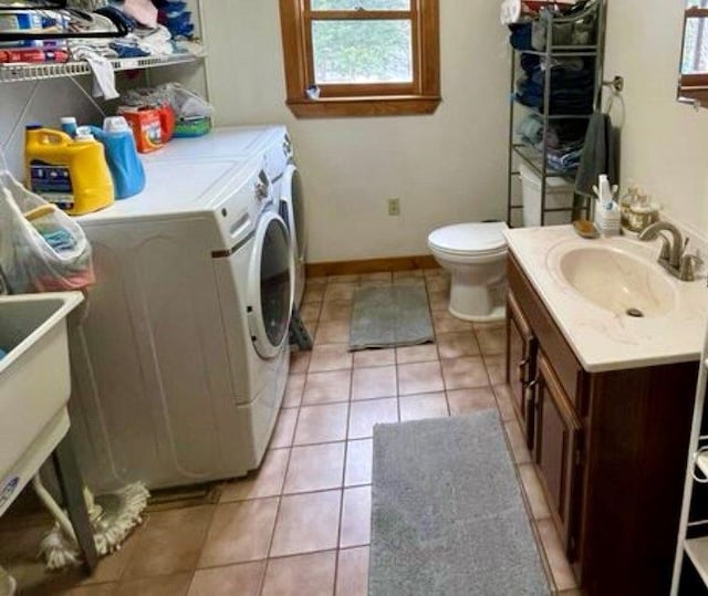 clothes washing area with light tile patterned flooring, independent washer and dryer, and sink