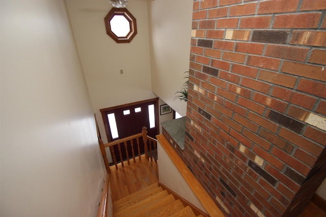 stairway featuring brick wall and hardwood / wood-style floors