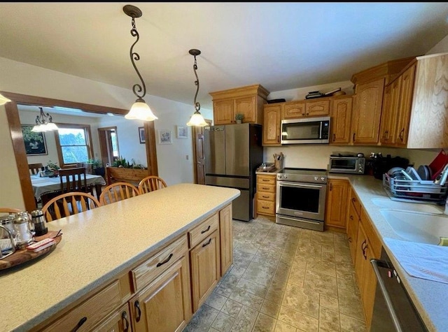 kitchen with pendant lighting, sink, stainless steel appliances, and a kitchen bar